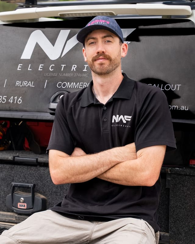 Nelson, owner of NAF Electrical, sitting on the tailgate of his work ute